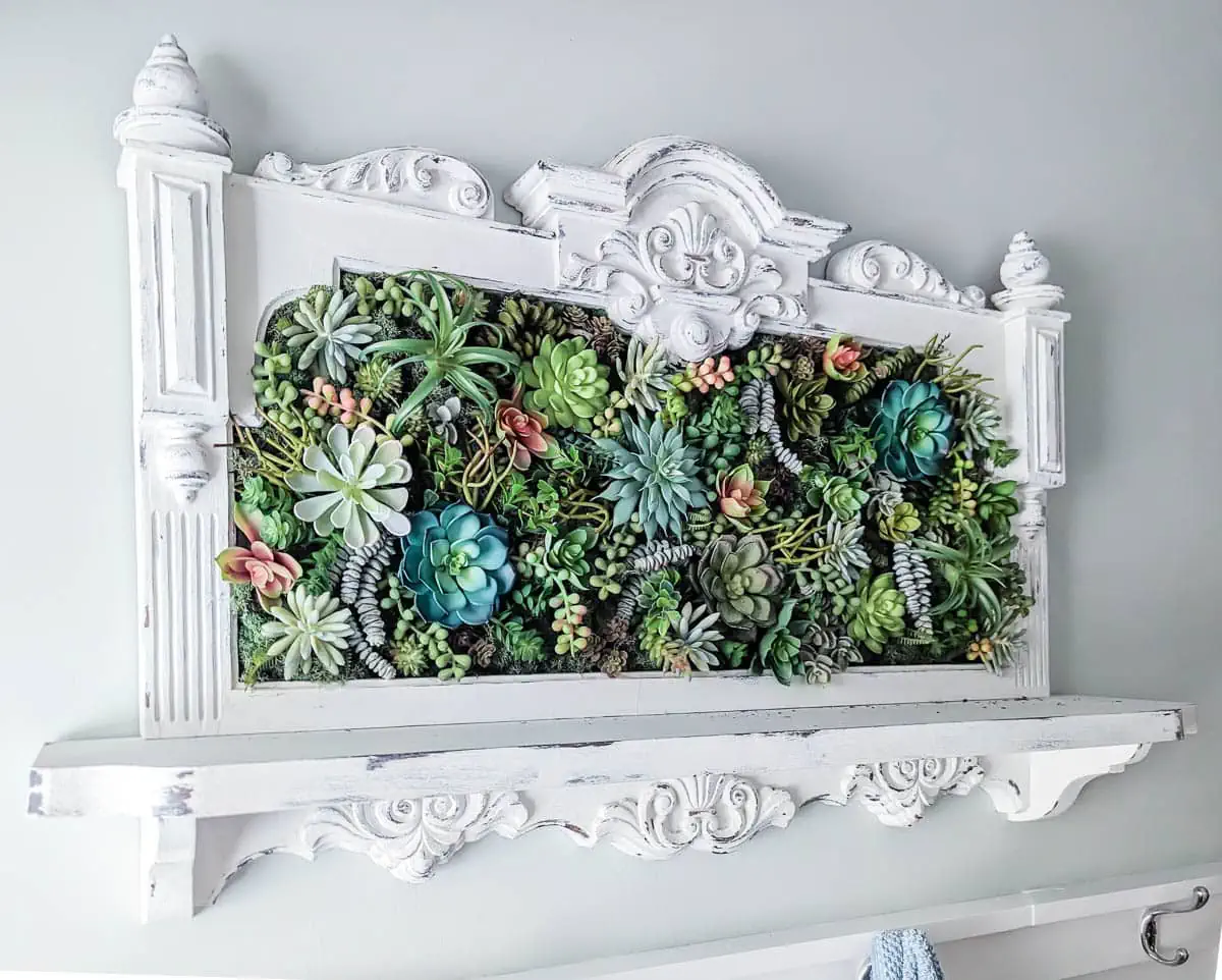 faux succulent wall art in an ornate white frame.