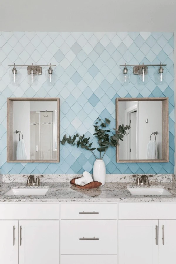 Bathroom with wood tile wall made from overlapping diamonds of wood painted in various shades of blue.
