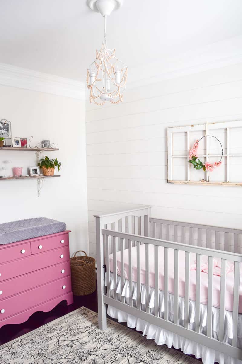Nursery with white shiplap style wall made from strips of plywood.