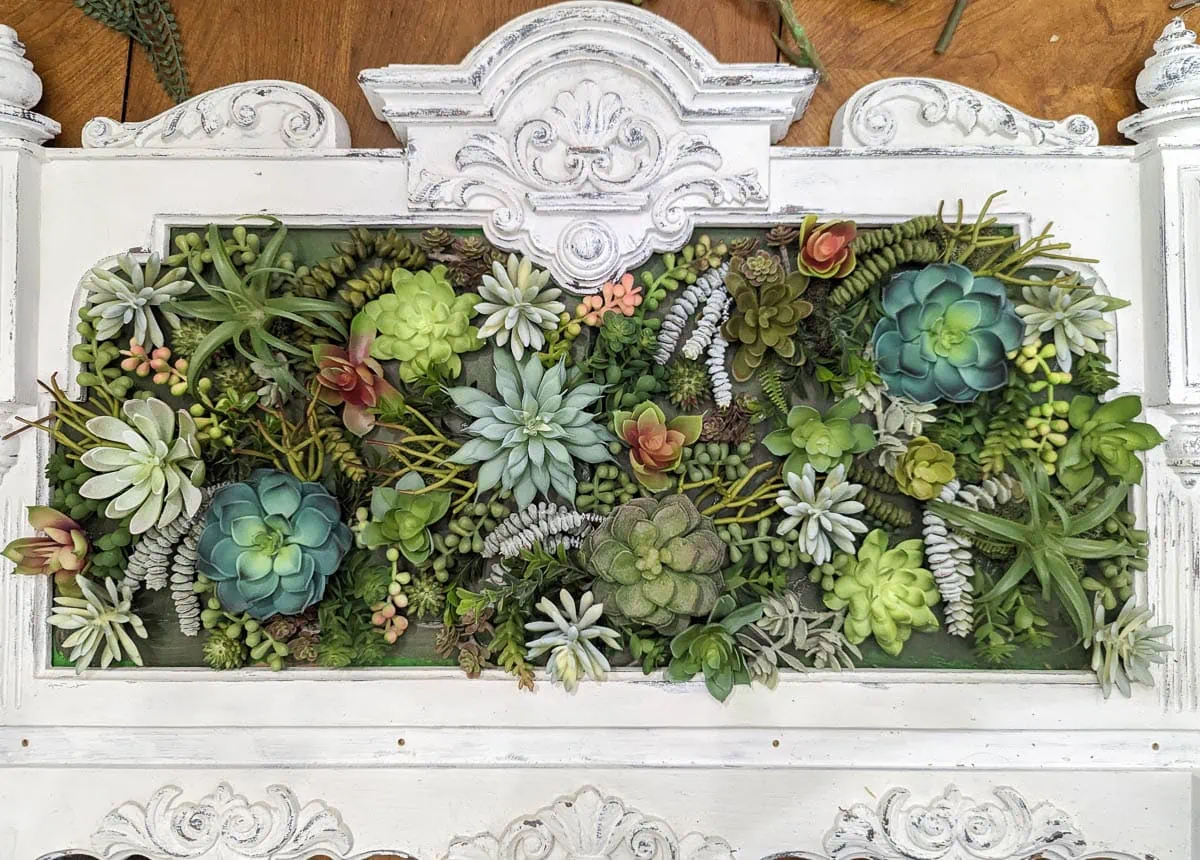 framed cardboard mostly covered with faux succulents.