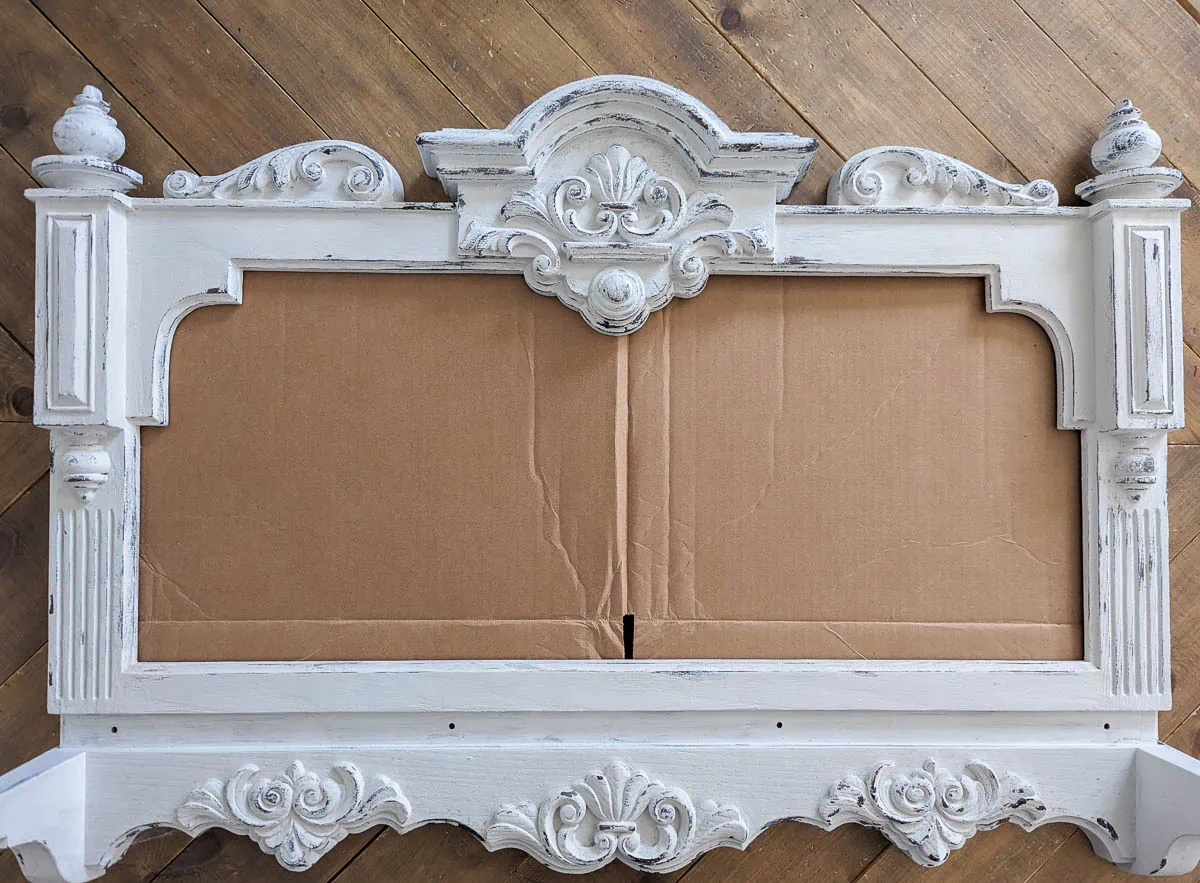 ornate frame paint white with cardboard in opening.