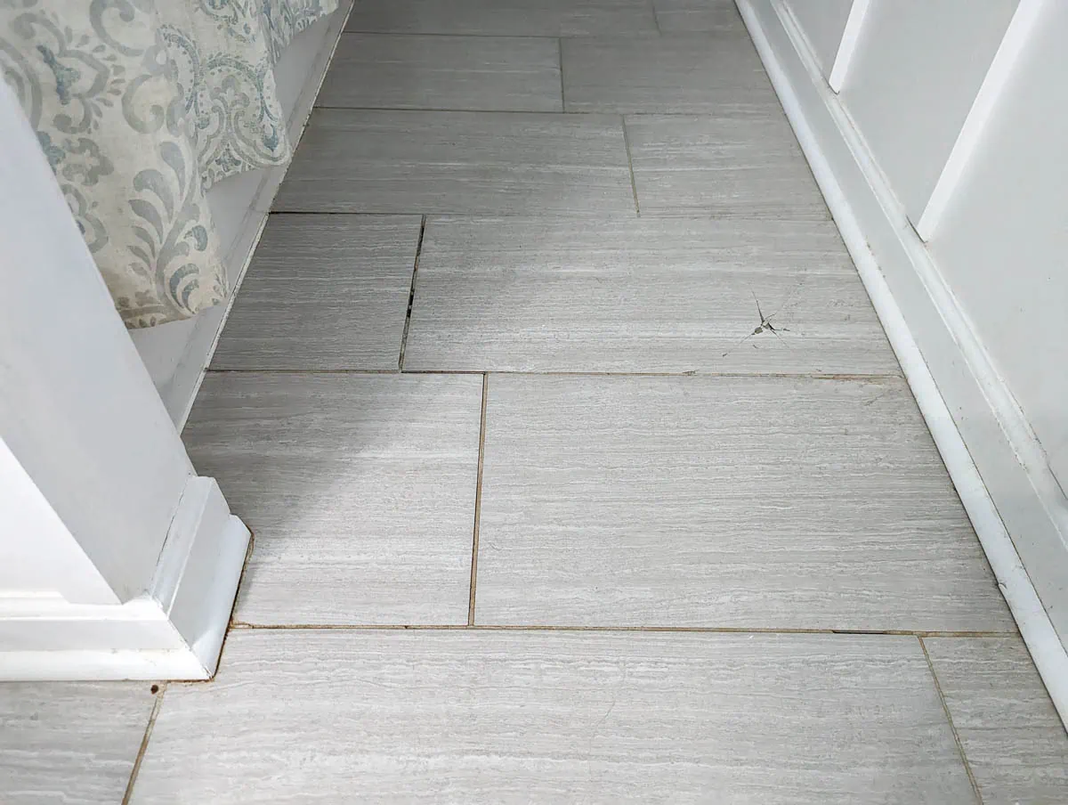 tile floor with stained, cracked grout and a cracked tile.