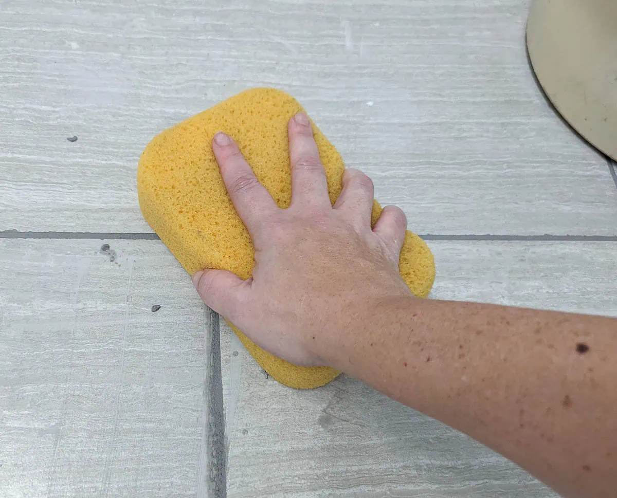 using a sponge to clean off excess grout.