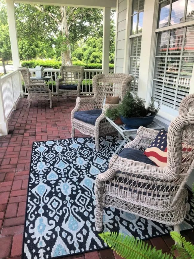 front porch with four wicker chairs arranged into two seating areas.