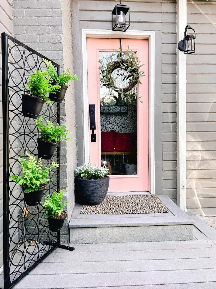 small front porch with pink front door and vertical planter wall.