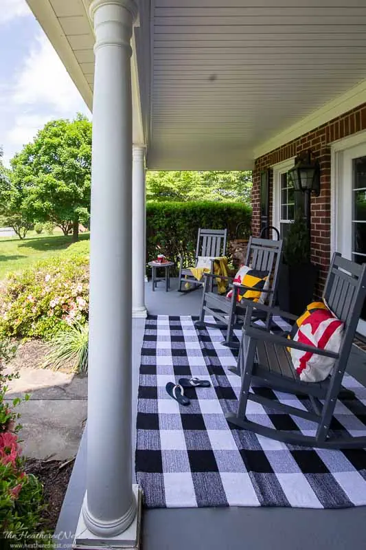 front porch with buffalo plaid rug and black rocking chairs.