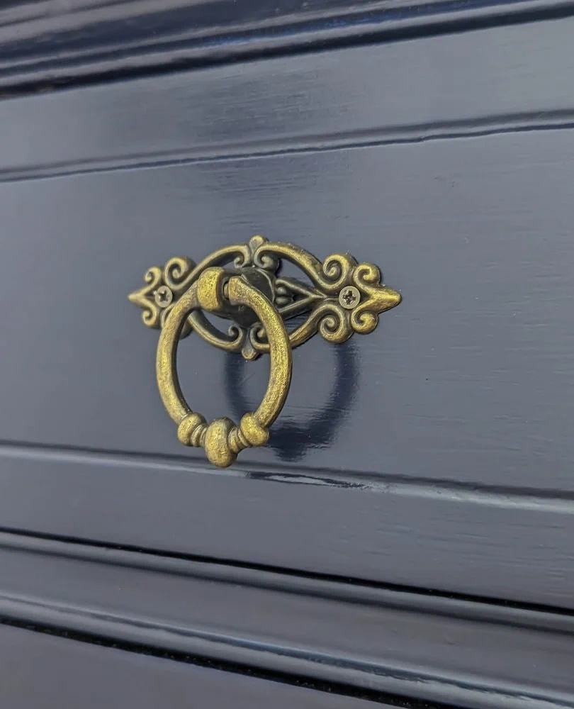 close up of brass hardware or blue dresser.