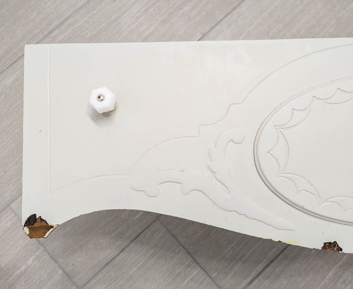 close up of two large chips from bottom drawer of vanity.
