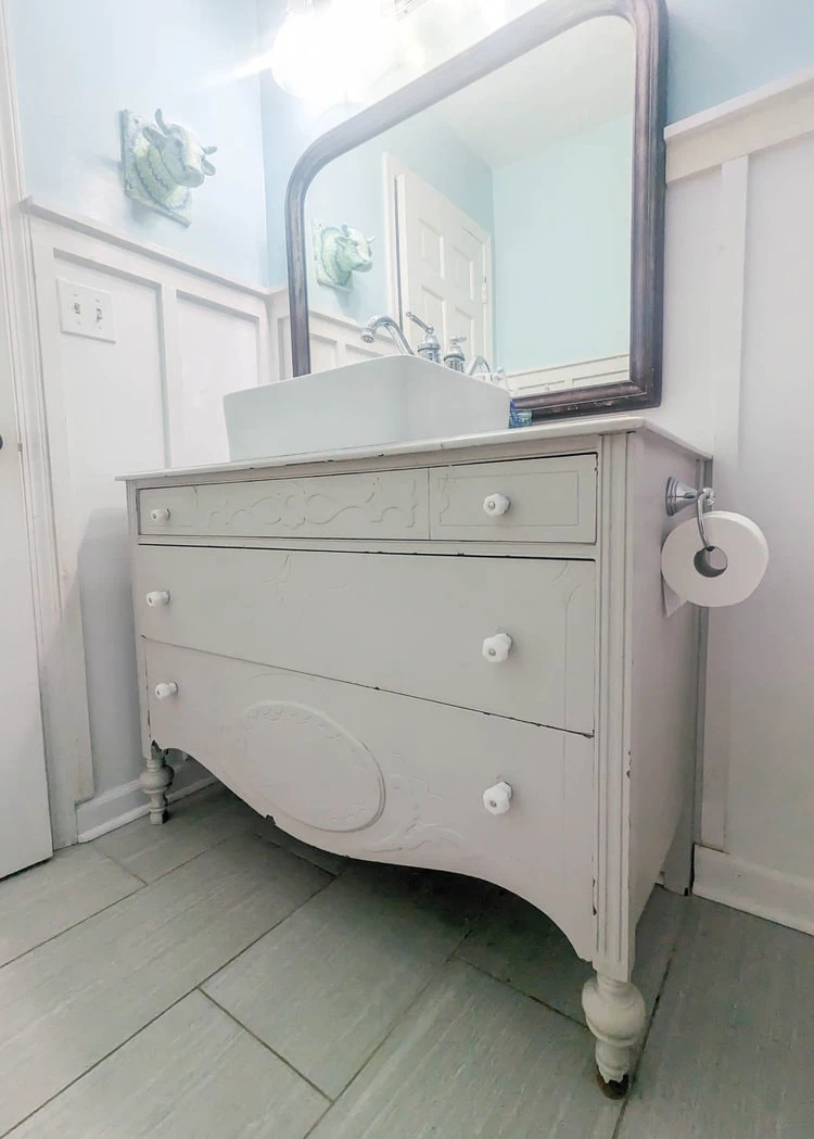 view of antique dresser bathroom vanity after seven years with several paint chips throughout.