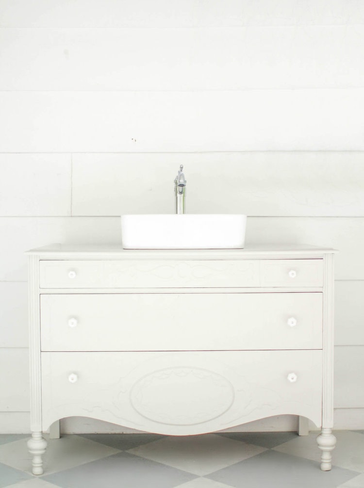 gray vintage dresser turned bathroom vanity in front of white shiplap wall.
