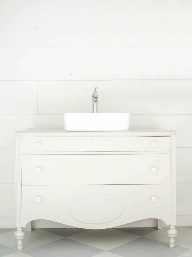 gray vintage dresser turned bathroom vanity in front of white shiplap wall.