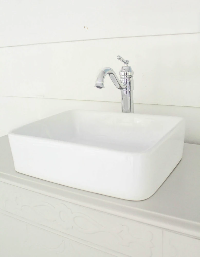 vessel sink and chrome faucet on top of antique dresser bathroom vanity.