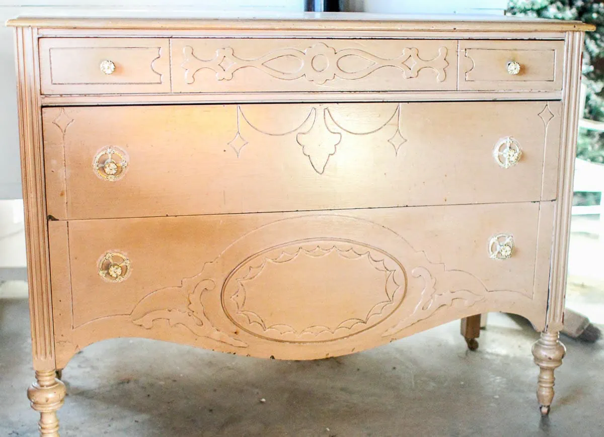 antique dresser with carved details and curved legs and many layers of paint.