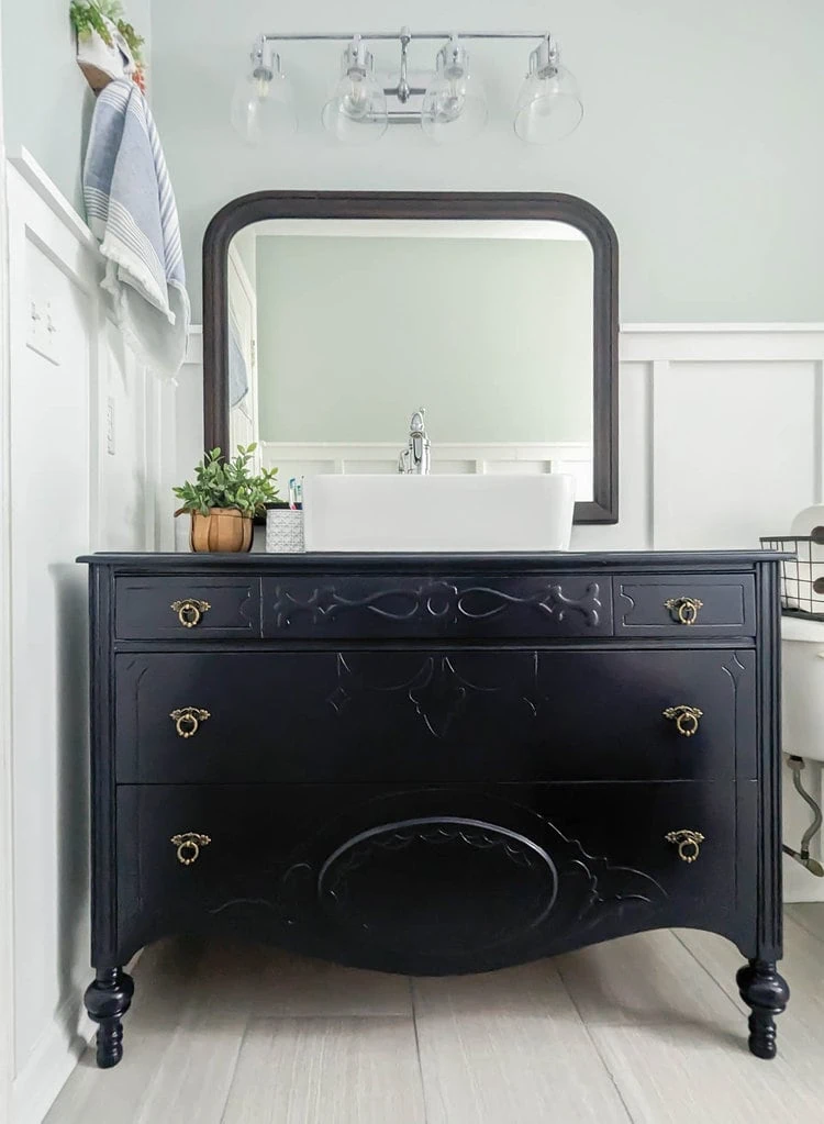 painted navy blue dresser in bathroom with vessel sink.