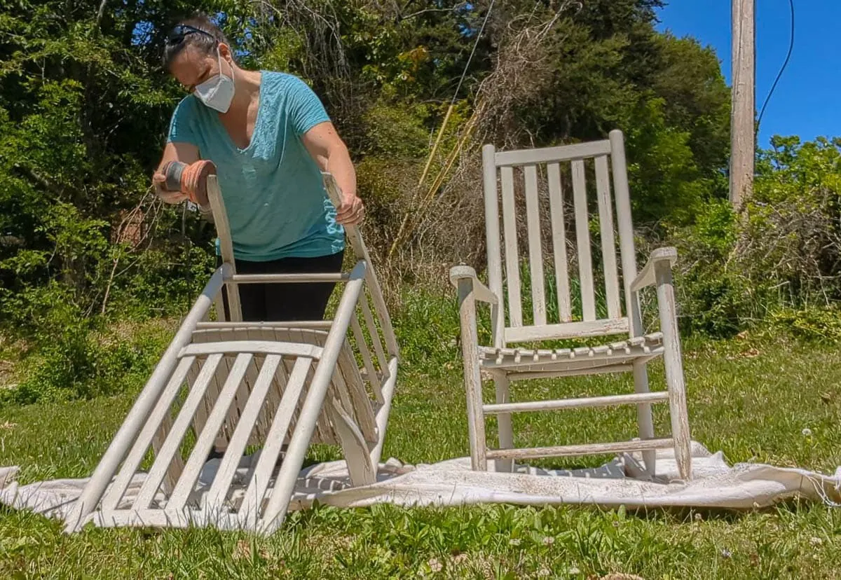 sanding old paint off rocking chair with orbital sander.