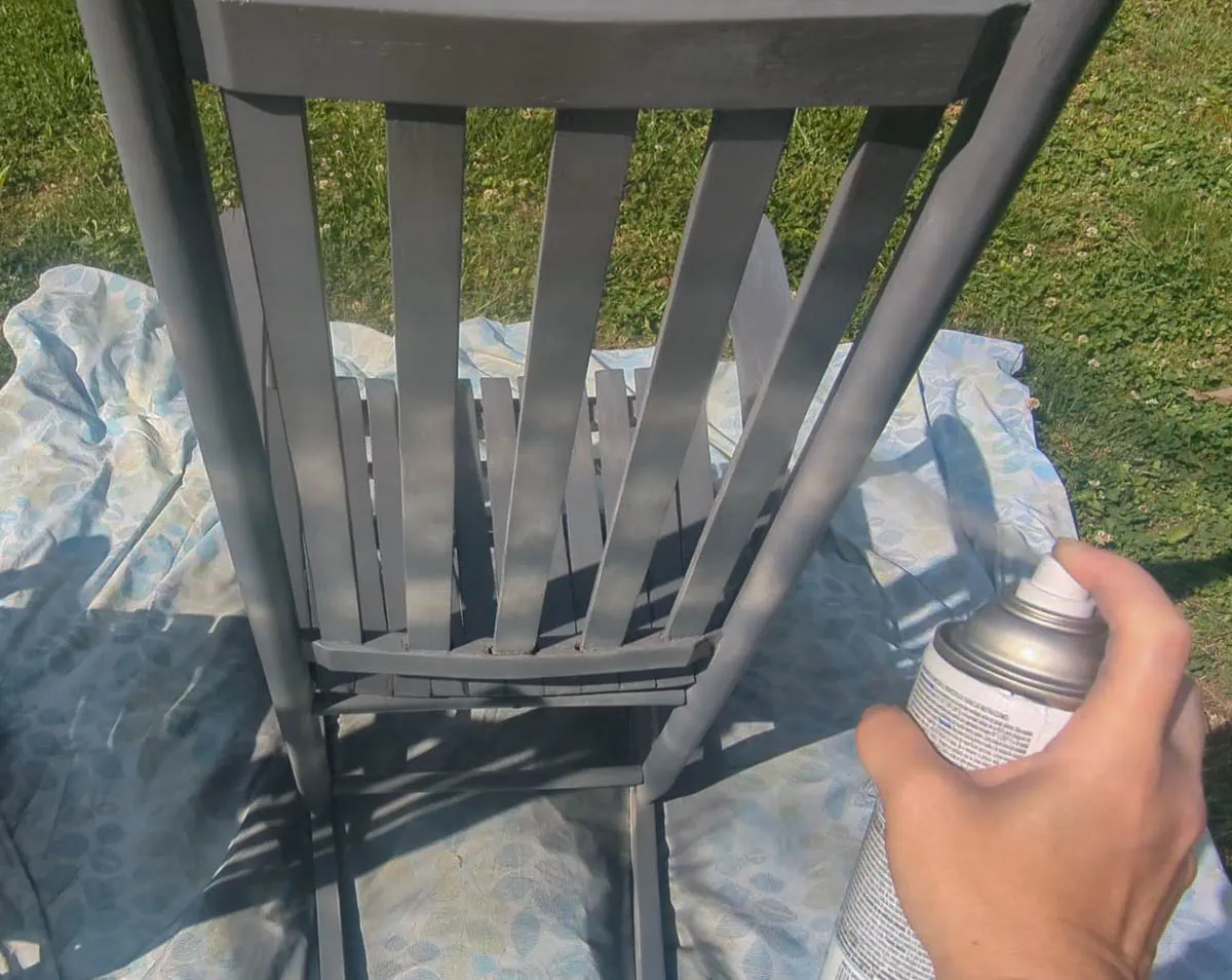 painting a chair back with spray paint.