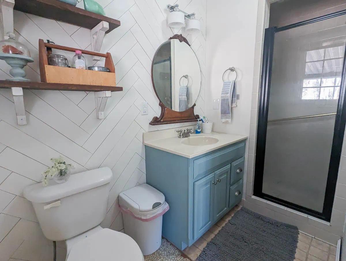 bathroom with blue vanity and vinyl floor before demo.