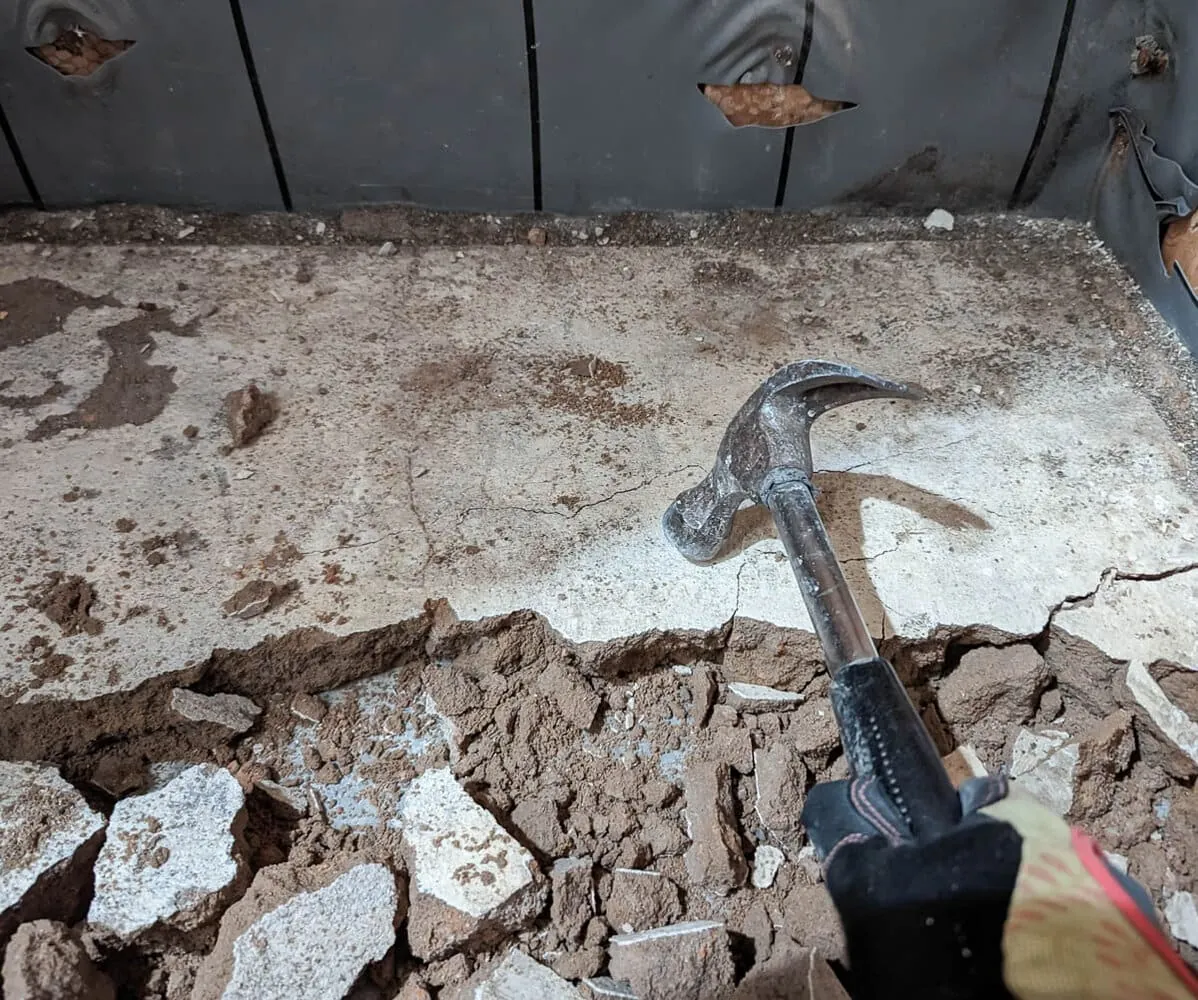 using a hammer to break up a concrete shower pan.