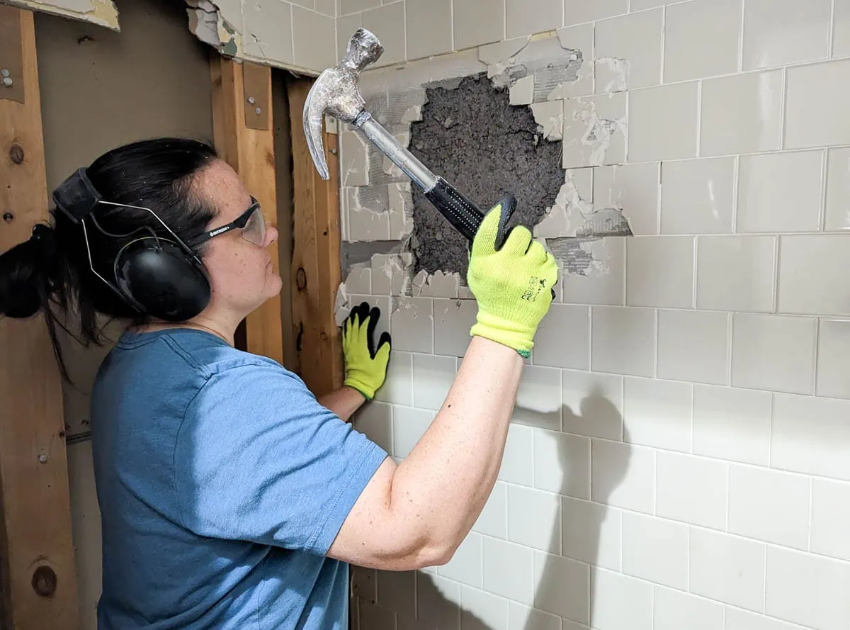 using a hammer to break up tile walls.