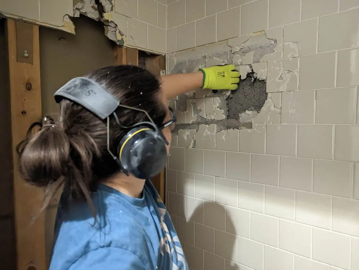 pulling broken up tiles off wall.