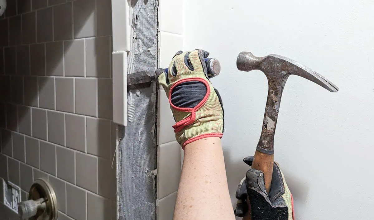 using a hammer and chisel to remove tile.