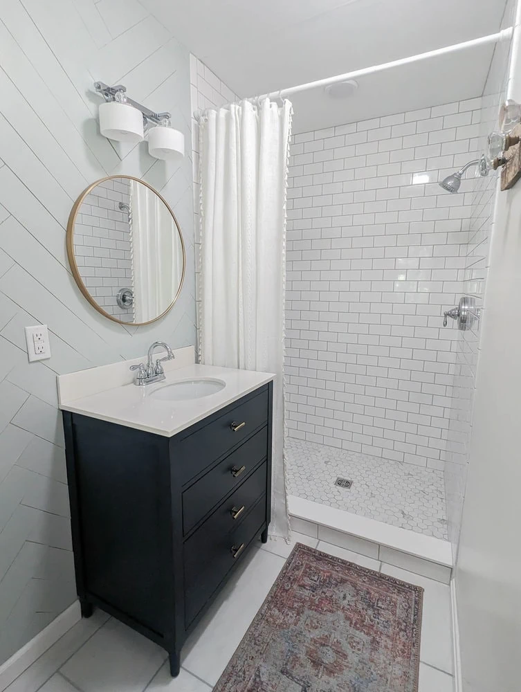 remodeled bathroom with subway tile walls, mosaic tile shower floor, solid threshold, and large porcelain tile floor.