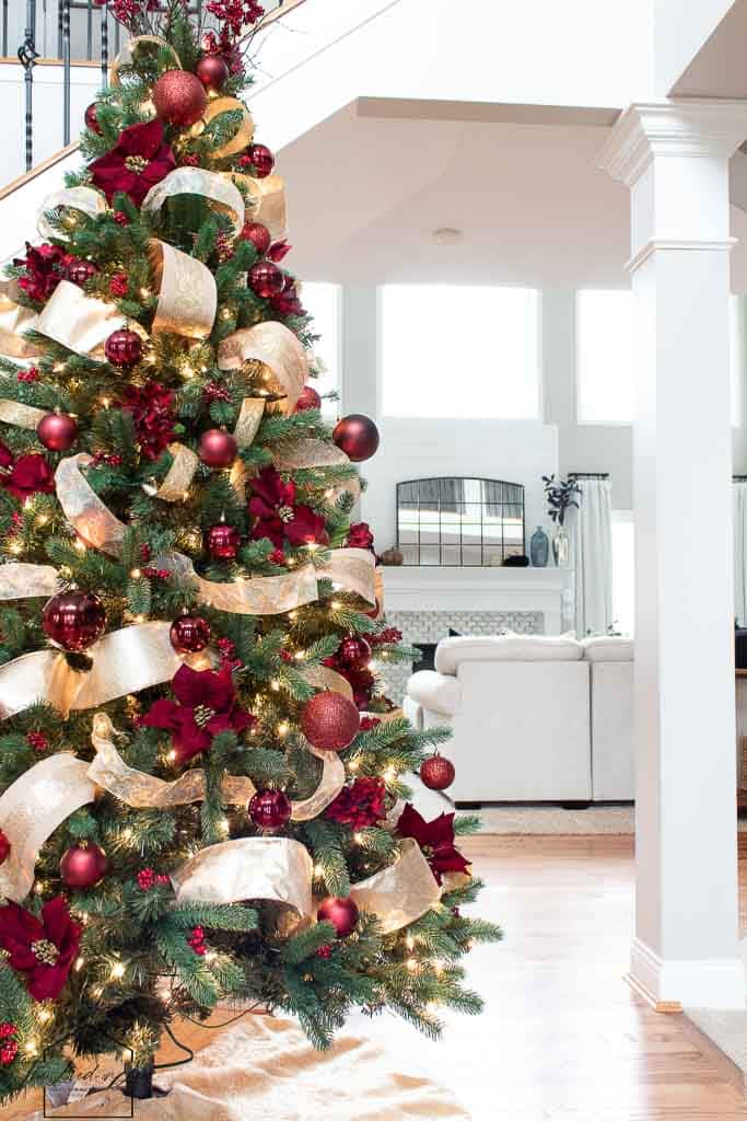 Christmas tree with burgundy ornaments and gold ribbon.