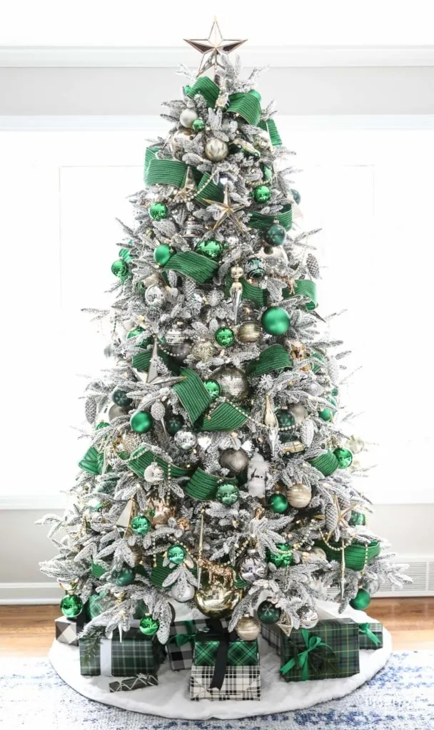 White Christmas tree with green ribbon and gold ornaments.