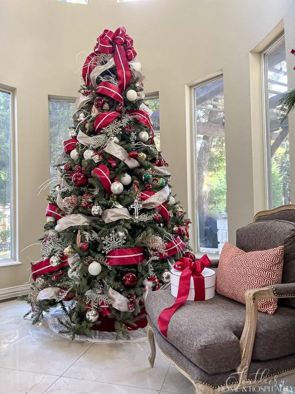 Christmas tree with gold and red decorations including a bow topper and lots of ribbon.