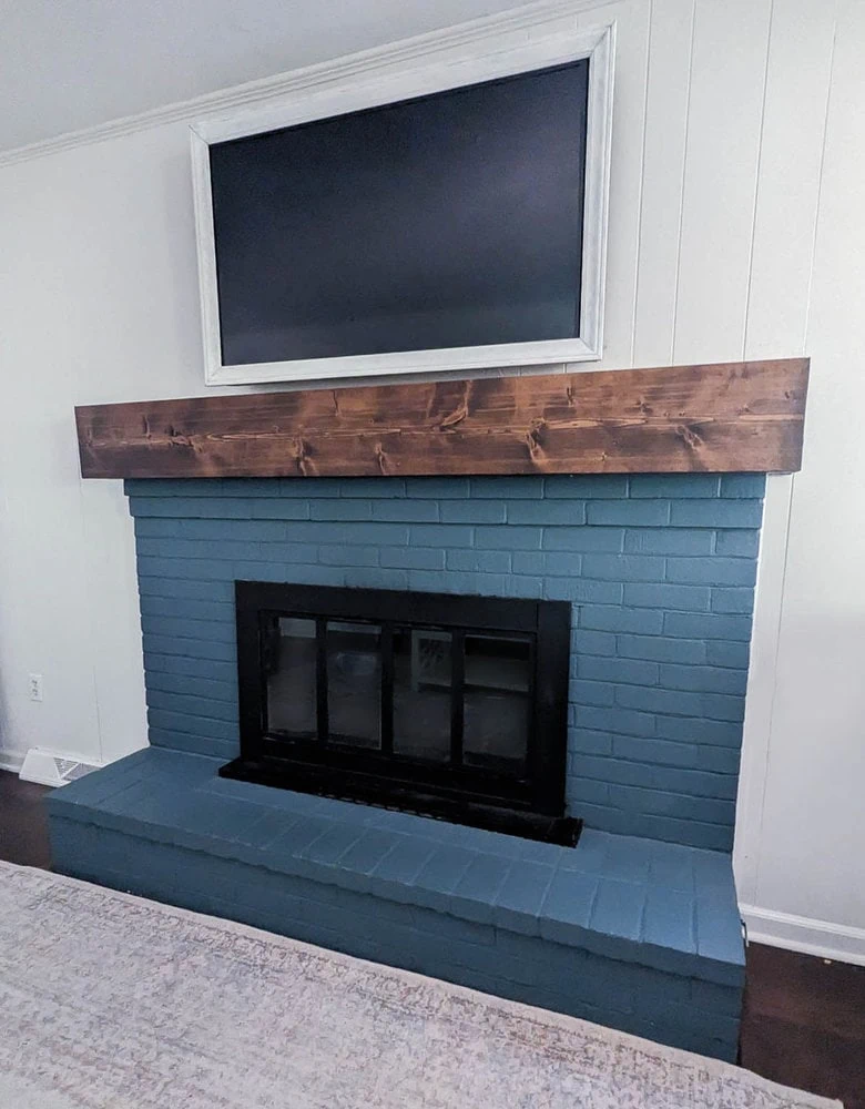 Brick fireplace painted blue with thick wood mantel.