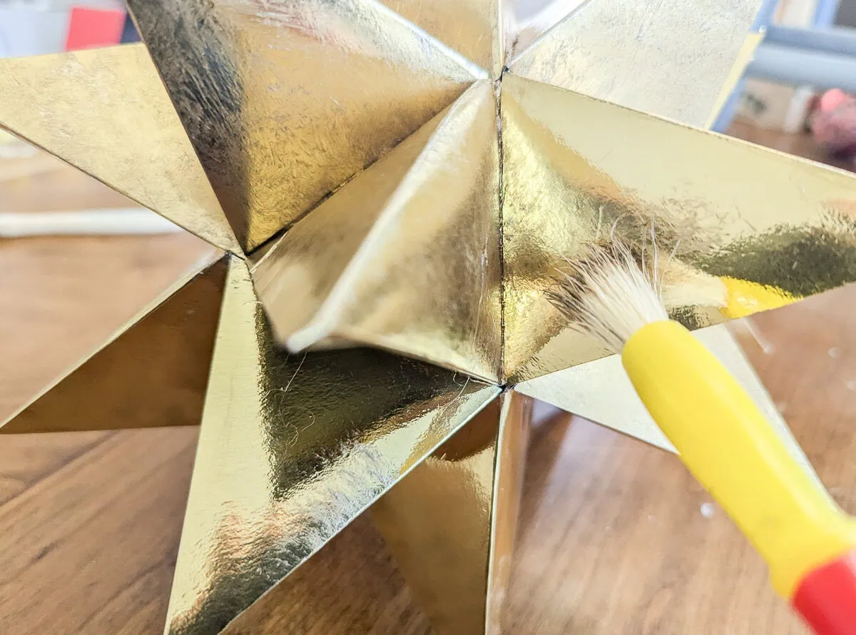 aging a gold foil star with paint and paintbrush.