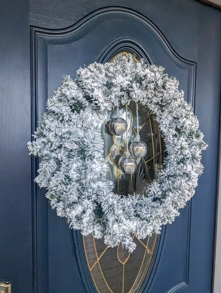 diy flocked wreath hanging on door with glass inset.