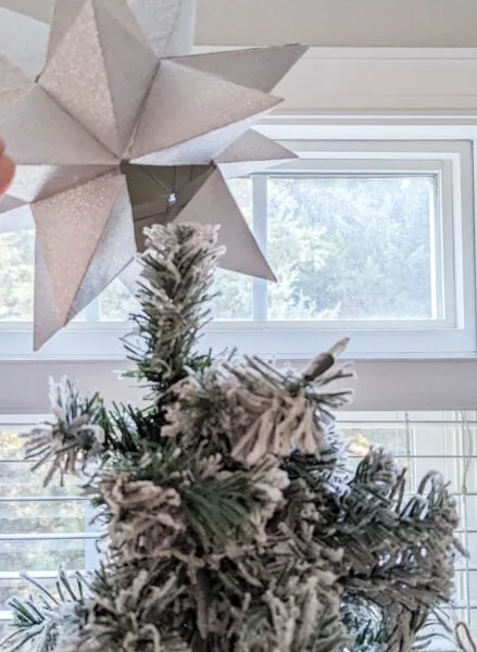 putting diy star onto Christmas tree.