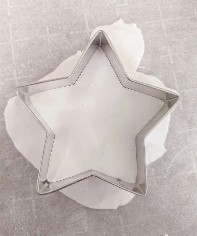 cutting clay with a star shaped cookie cutter.
