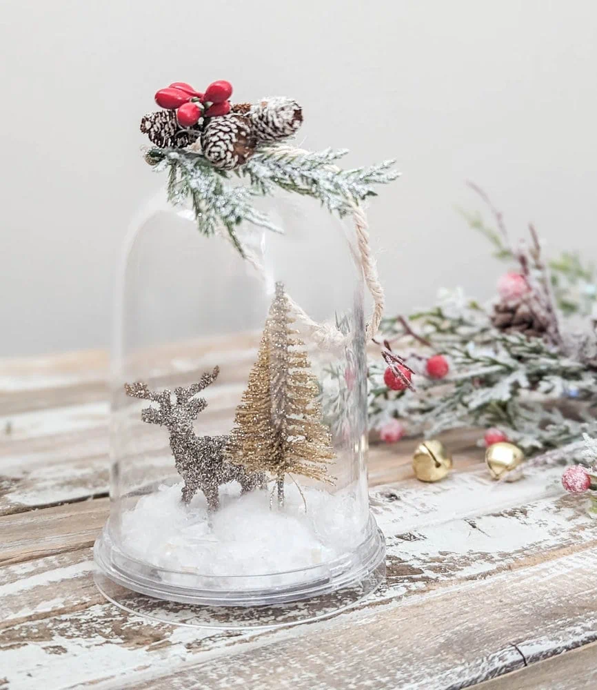 diy snow globe ornament with glittery deer and tree inside.