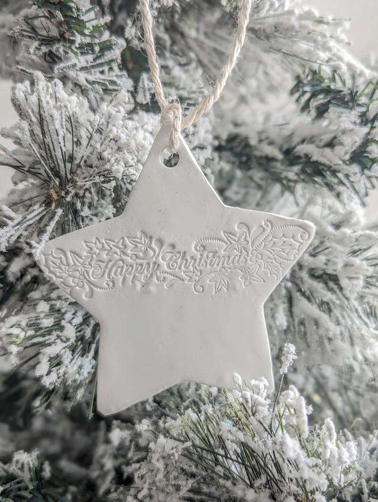 a diy clay ornament hanging on a Christmas tree.