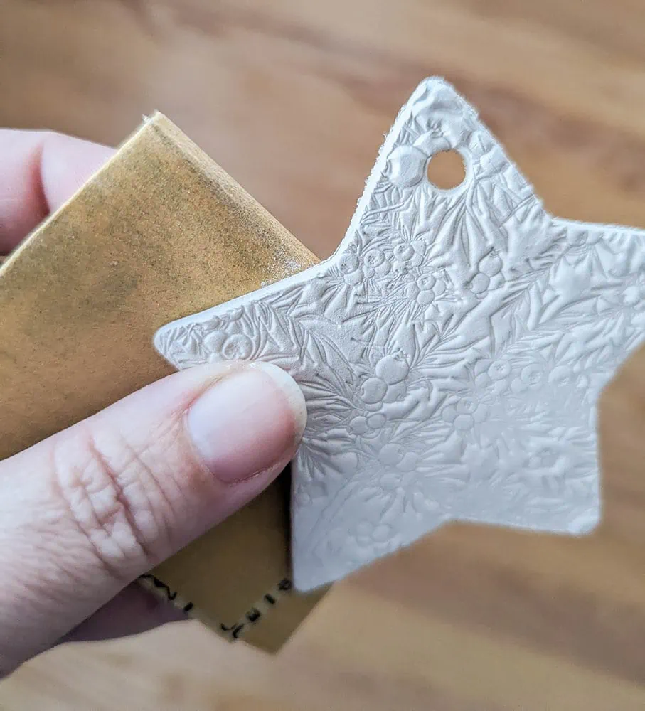 sanding the rough edges from a clay ornament.