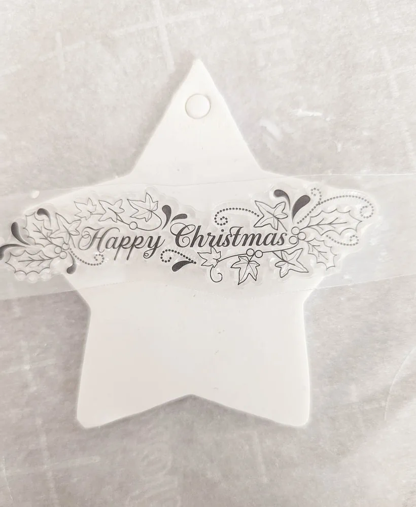 stamping onto a clay ornament with a Happy Christmas stamp.