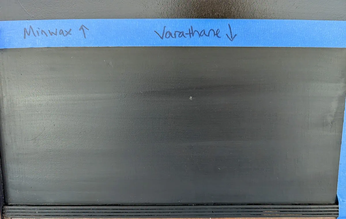 section of black paint with a grayish tint and streaks where varathane was applied.