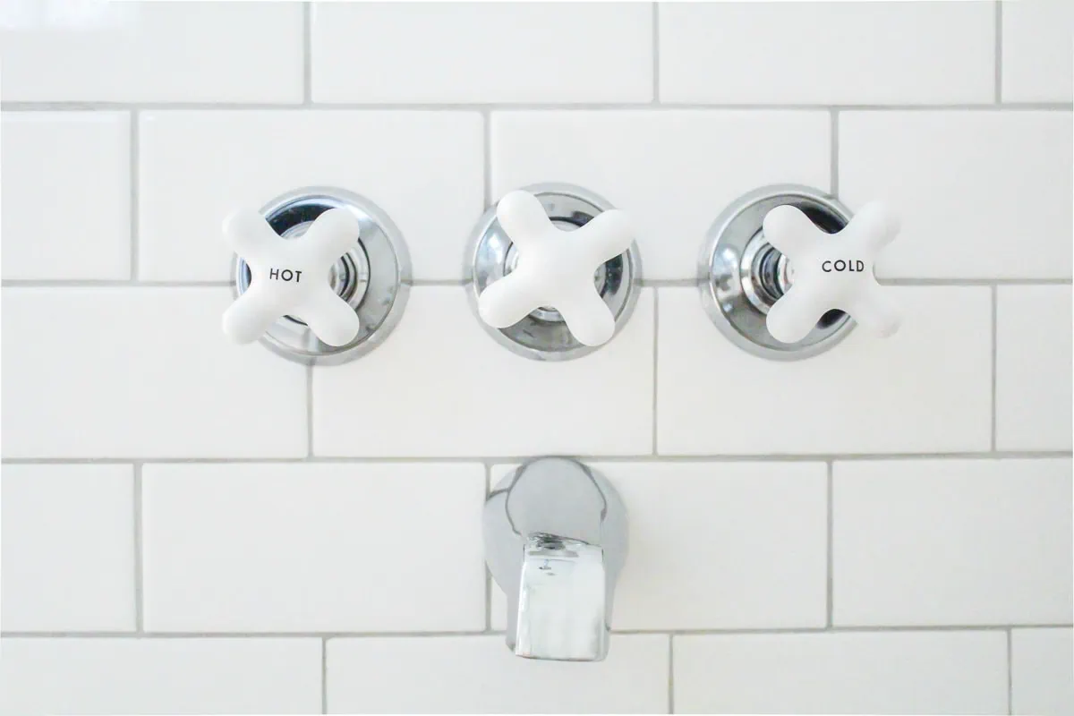 subway tile shower with vintage style white knobs.