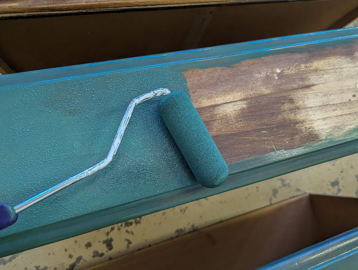 rolling green paint onto a drawer.