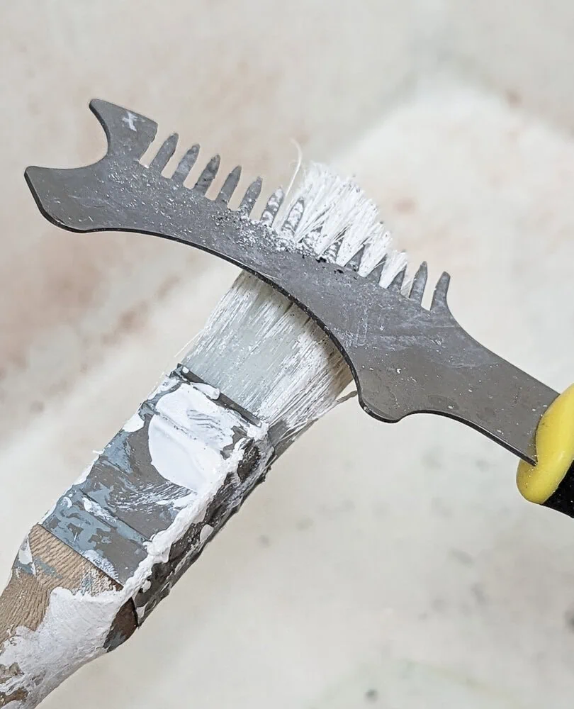 cleaning a paint brush with a cleaning tool.