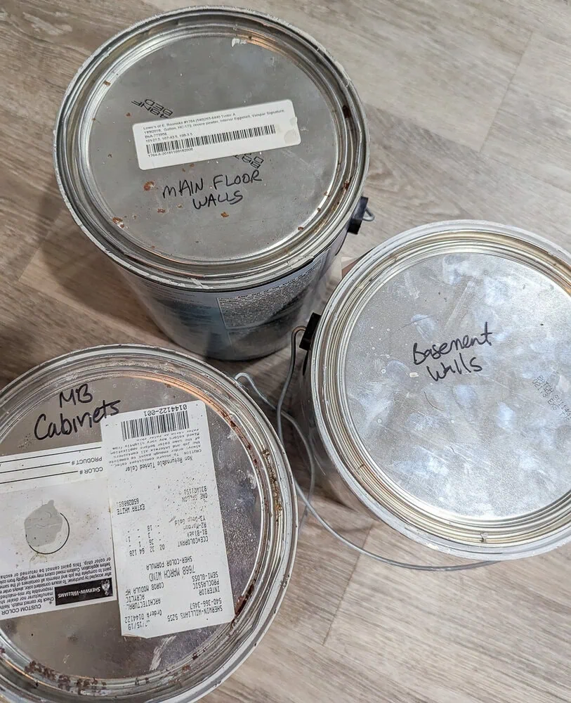 three paint cans labeled with the rooms they were used in.