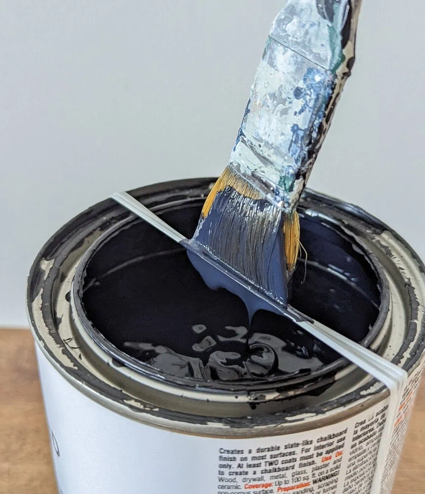 paint can with rubber band around it for wiping paint brush.