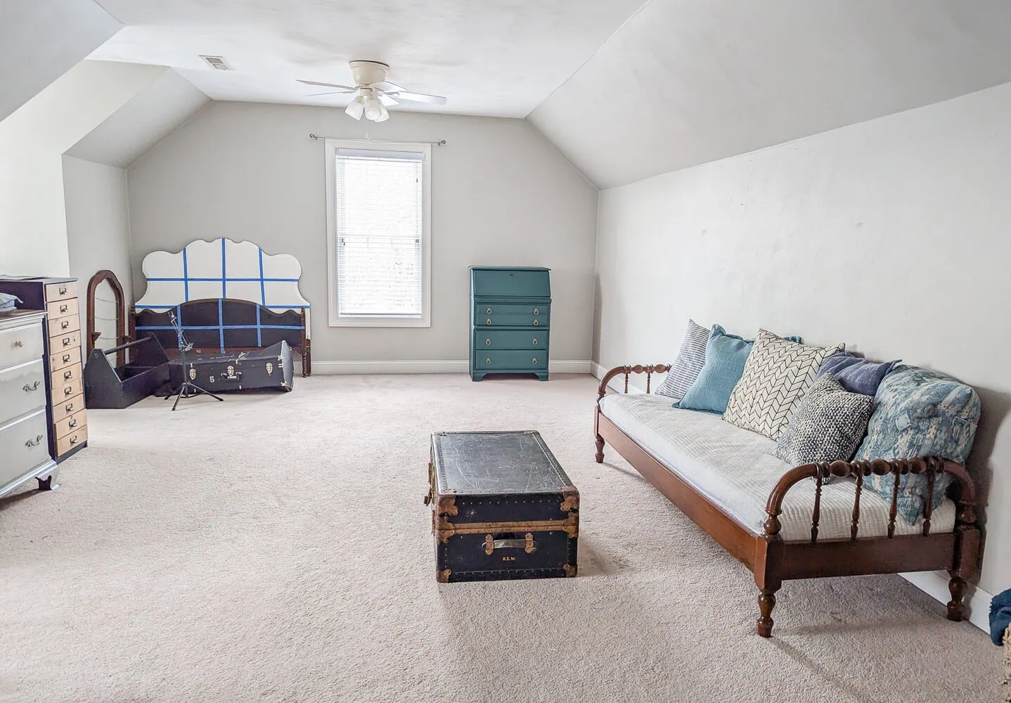 bonus room with an old daybed, trunk, and various other furniture.