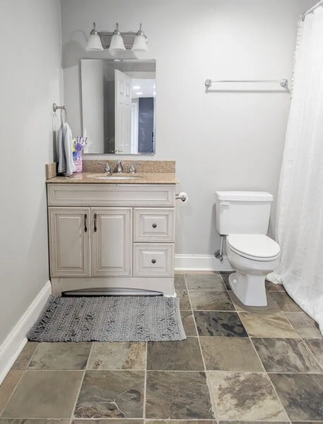 small bathroom with slate floor and cream vanity.