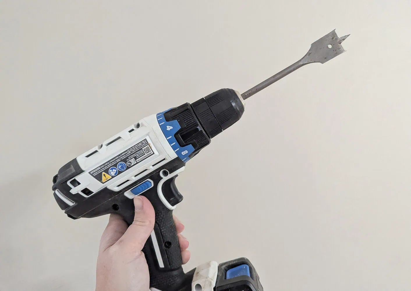 drill with spade bit for drilling hole in back of dresser.