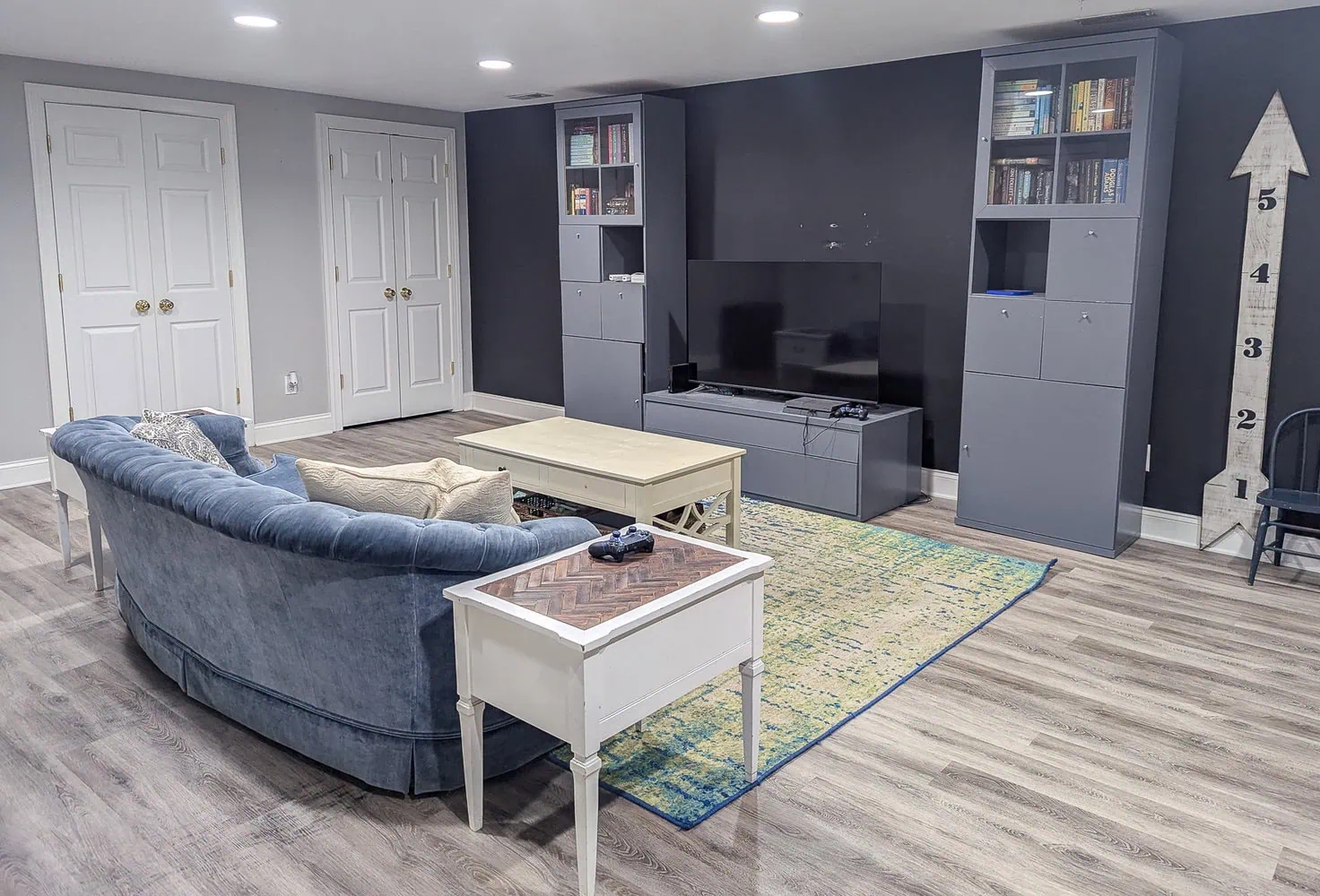 basement family room with couch, TV stand, and bookcases.