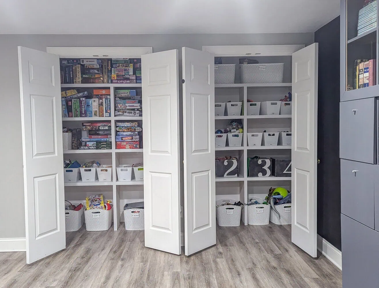 two closets with DIY shelving full of bins of toys and games.