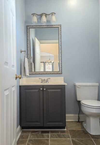 powder room with slate floor and navy vanity.